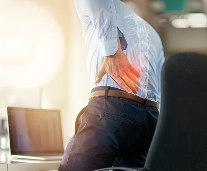 Man clutching his lower back in pain, with a glowing spine overlay.