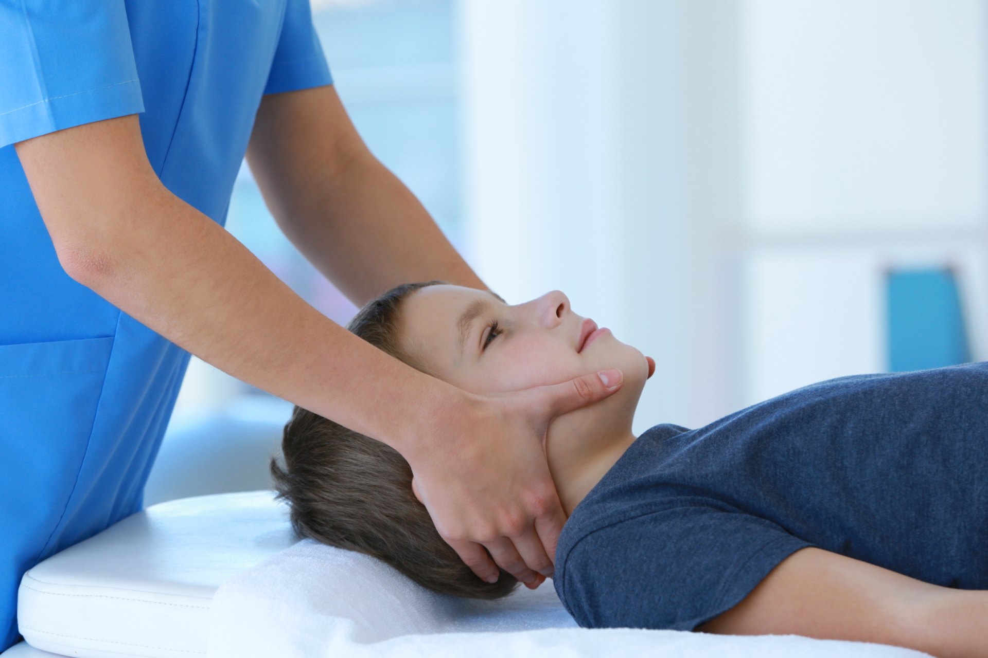 Pediatric chiropractor adjusting a childs neck on an examination table.