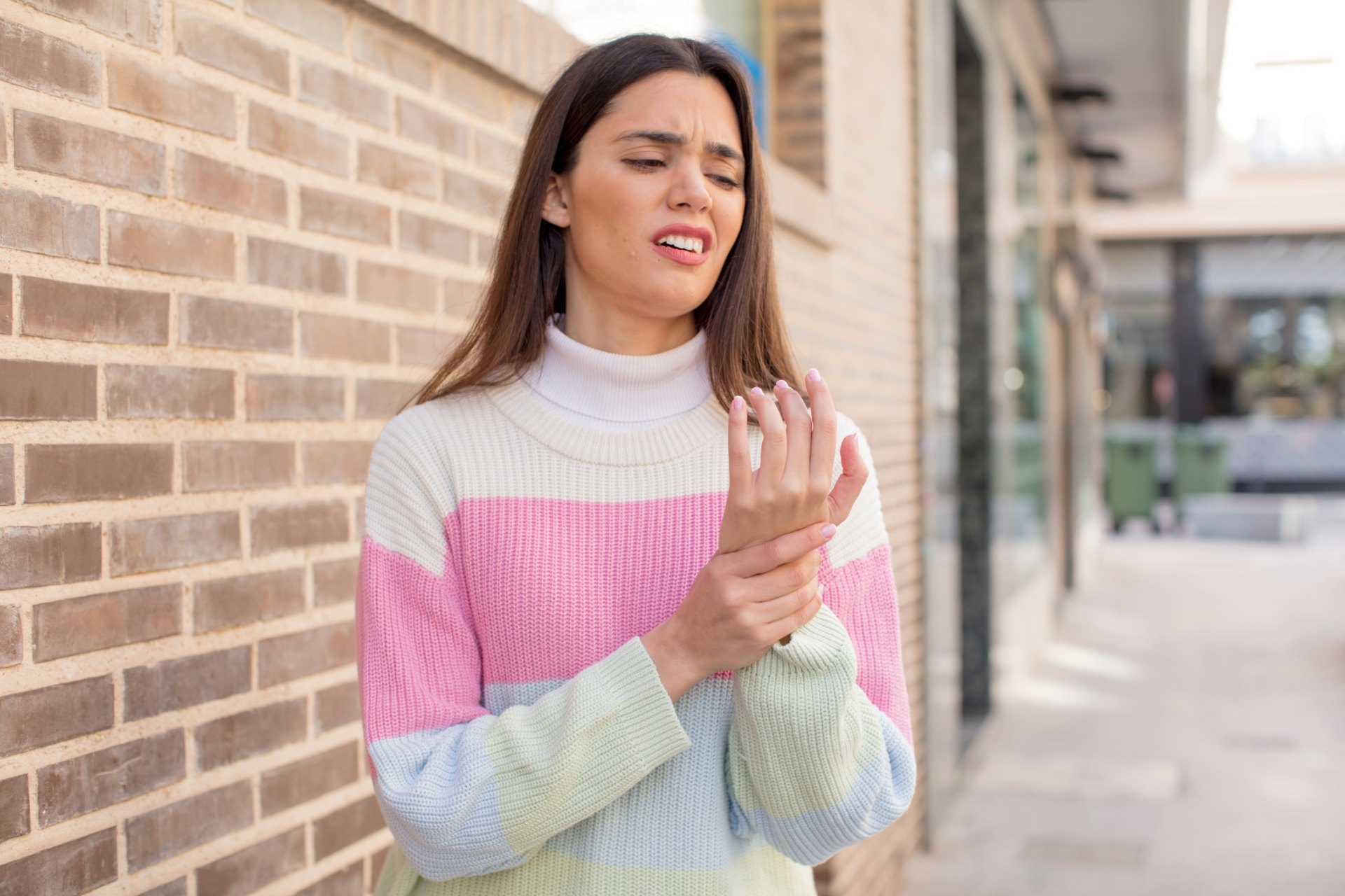 Person holding wrist, showing discomfort, for neuropathy treatment