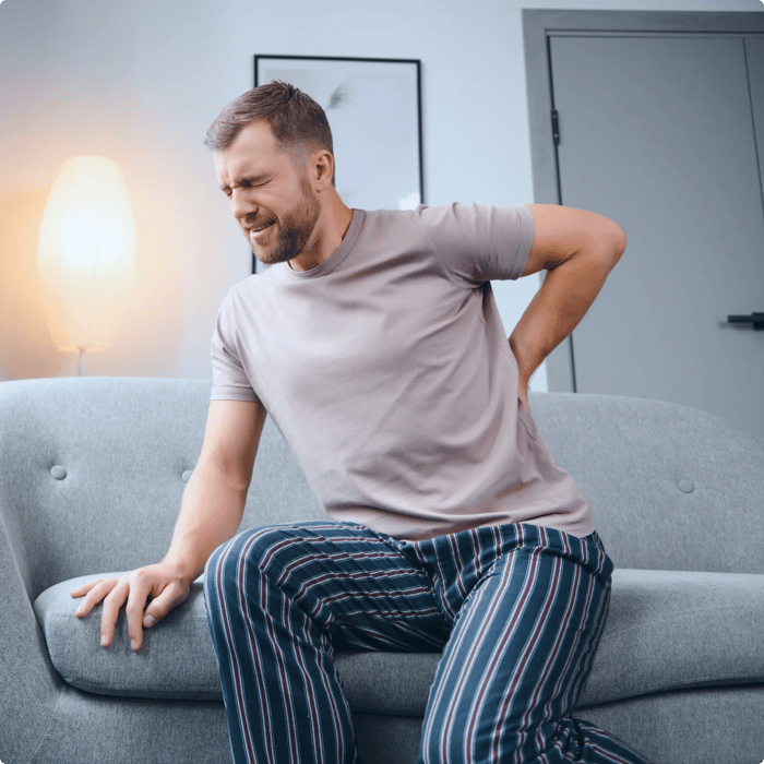 Man grimacing and clutching his hip in pain