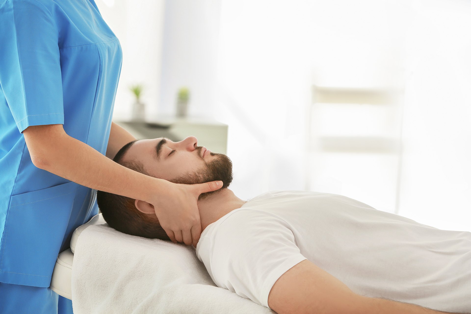 Chiropractor performing neck adjustment on patient