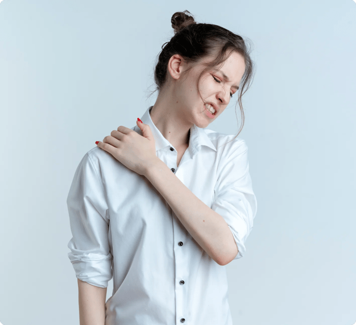 Young woman grimacing and clutching her left shoulder in pain.