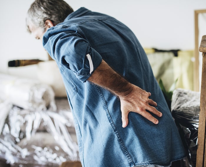 Man clutching his lower back in pain, possibly from lifting or moving.